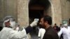 An Afghan health worker, left, takes the temperature of a guest to check for coronavirus at the entry gate of presidential palace during in an inauguration ceremony for President Ashraf Ghani in Kabul, Afghanistan, March 9, 2020. 