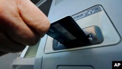 FILE - A person inserts a debit card into an ATM in Pittsburgh, Pennsylvania. The U.S. Supreme Court will allow a class action lawsuit about ATM fees to go forward. 