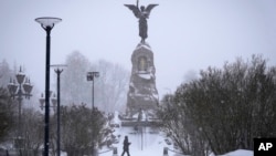 Muškarac prolazi pored spomenika mornarima bojnog broda Rusalka (Sirena) tokom snježnih padavina u Talinu, Estonija, petak, 12. januara 2024. (AP Photo/Sergei Grits)