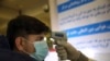 FILE - An Afghan health worker takes the temperature of a passenger as a preventive measure for Coronavirus, during screening of travelers who arrived from China, at the Hamid Karzai International Airport in Kabul, Feb. 3, 2020.