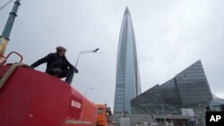 Seorang pekerja duduk di truk tangki airnya di sebelah menara bisnis Lakhta Centre, markas besar monopoli gas Rusia Gazprom di St. Petersburg, Rusia, 27 April 2022. (Foto: Dmitri Lovetsky/AP Photo)