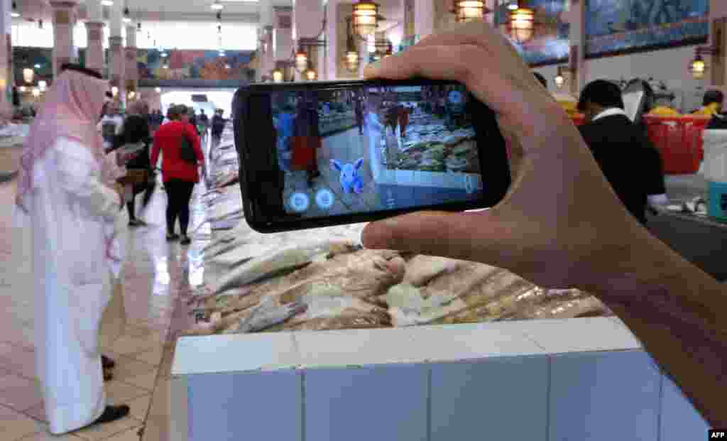 Seorang menggunakan aplikasi game Pokemon di sebuah pasar ikan di Kuwait City, Kuwait.