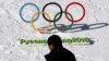 FILE - A man walks by the Olympic rings with a sign of 2018 Pyeongchang Olympic Winter Games, in Pyeongchang, South Korea, Feb. 3, 2017. 
