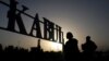 FILE - People stand in front of a sign at the international airport in Kabul, Afghanistan, Sept. 9, 2021. 