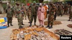 FILE - Military officials stand near ammunitions seized from suspected members of Hezbollah after a raid of a building in Nigeria's northern city of Kano, May 30, 2013.