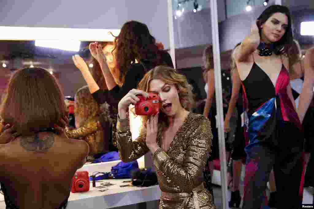 Model Karlie Kloss plays with a camera during a presentation for the Diane von Furstenberg Fall/Winter 2016 collection presentation at New York Fashion Week, Feb. 14, 2016.