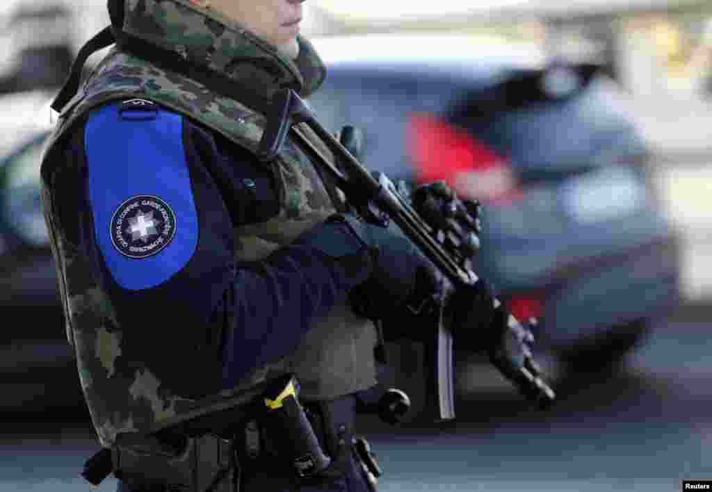 A heavily armed Swiss customs officer stands guard at the Swiss-French customs post of Bardonnex near Geneva. Geneva raised its alert level Thursday and said it was looking for suspects who, according to national officials, had possible links to terrorism.