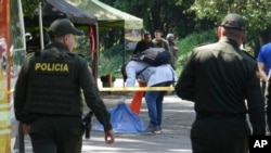 Tim penyidik forensik memeriksa jenazah seorang pria yang tewas setelah sebuah motor yang dilengkapi dengan bom meledak di pos pemeriksaan di komunitas Las Peñas di Jamundi, Kolombia, pada 7 Desember 2024. (Foto: AP/Juan B Diaz)