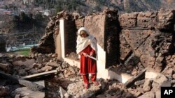 A Pakistani Kashmiri woman stands amid debris of her home that reportedly was destroyed by cross border shelling from Indian troops, in Neelum Valley, at the Line of Control in Pakistani Kashmir, Dec. 23, 2019. 