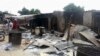 Residents stand in front of destroyed properties and houses following an attack in the northeast Nigerian village of Kawuri, Jan. 28, 2014. 