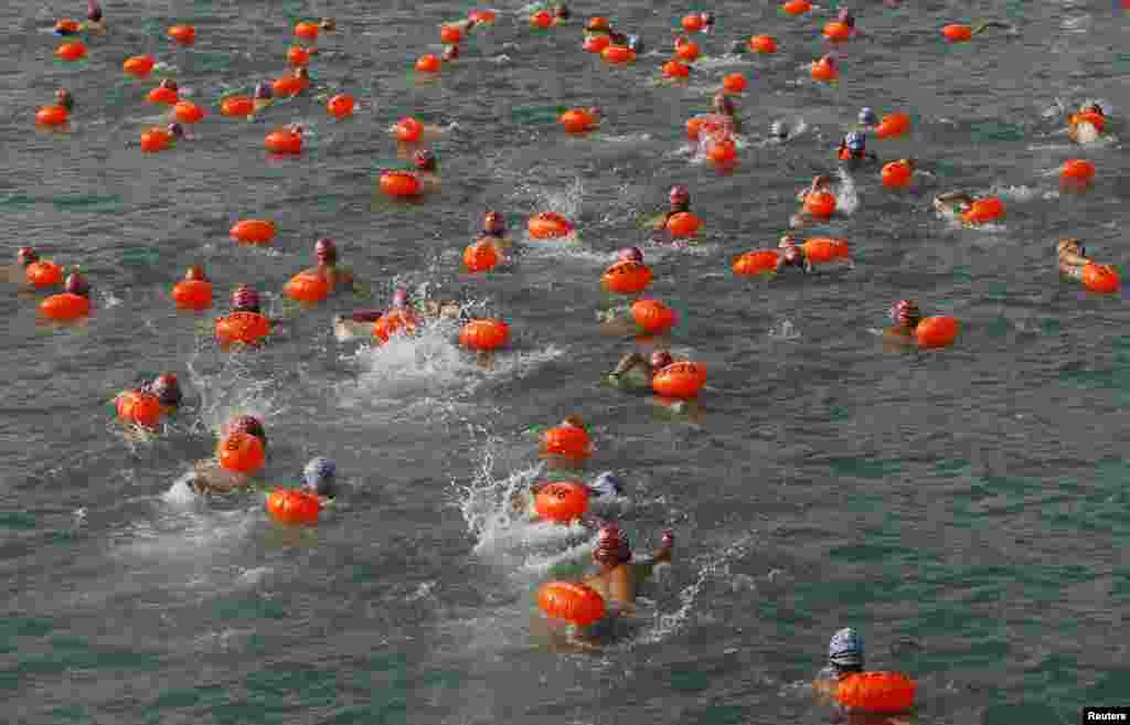 Swimmers, with buoys attached, compete in a cross harbor swimming event at Hong Kong's Victoria Harbour.