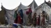 FILE - Children of Afghan refugees play outside tents in the Afghan Basti area on the outskirts of Lahore, Pakistan, June 19, 2021.