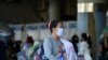 FILE PHOTO: A woman wearing a mask carries a baby at a bus station during the coronavirus disease (COVID-19) outbreak, in Bangkok
