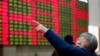 FILE - An investor gestures in front of the stock price monitor at a private securities company in Shanghai, China. 
