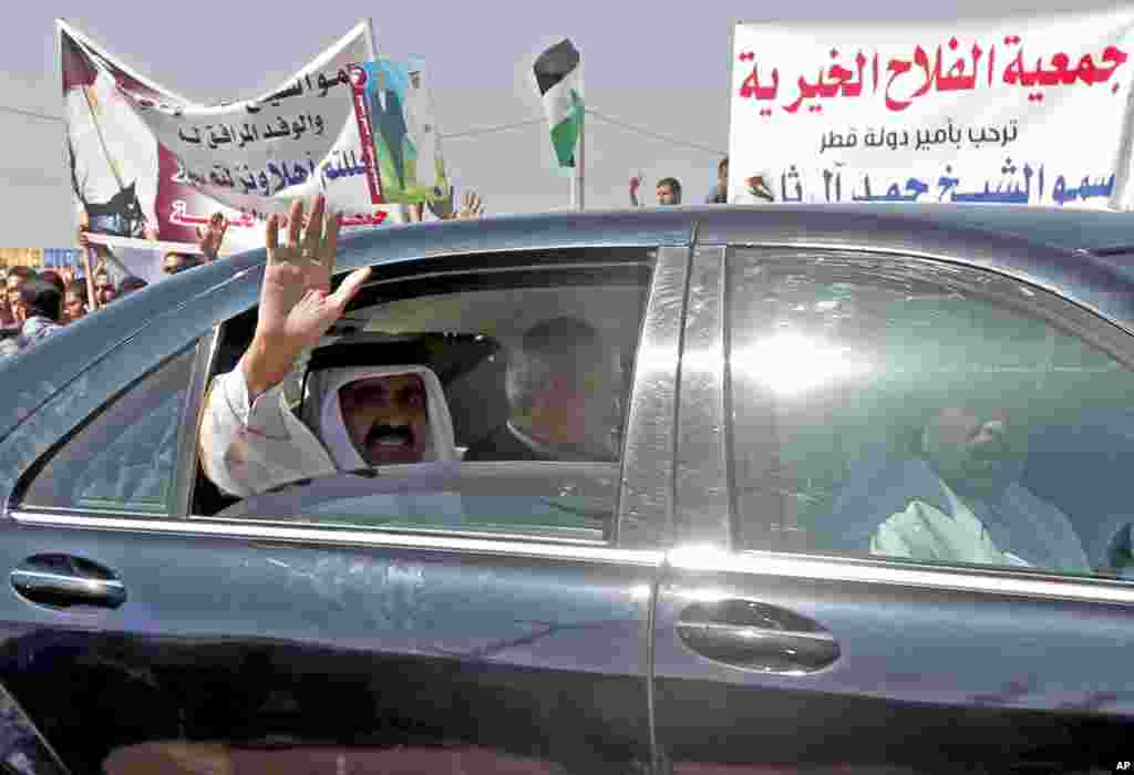 The Emir of Qatar Sheikh Hamad bin Khalifa al-Thani waves to crowds as he sits next to Gaza's Hamas prime minister Ismail Haniyeh following a welcome ceremony in Rafah, southern Gaza Strip, Tuesday, October 23, 2012.