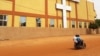 Des gens passent à moto devant une église dans le quartier de Dassasgo à Ouagadougou, au Burkina Faso, le 25 mars 2020. 