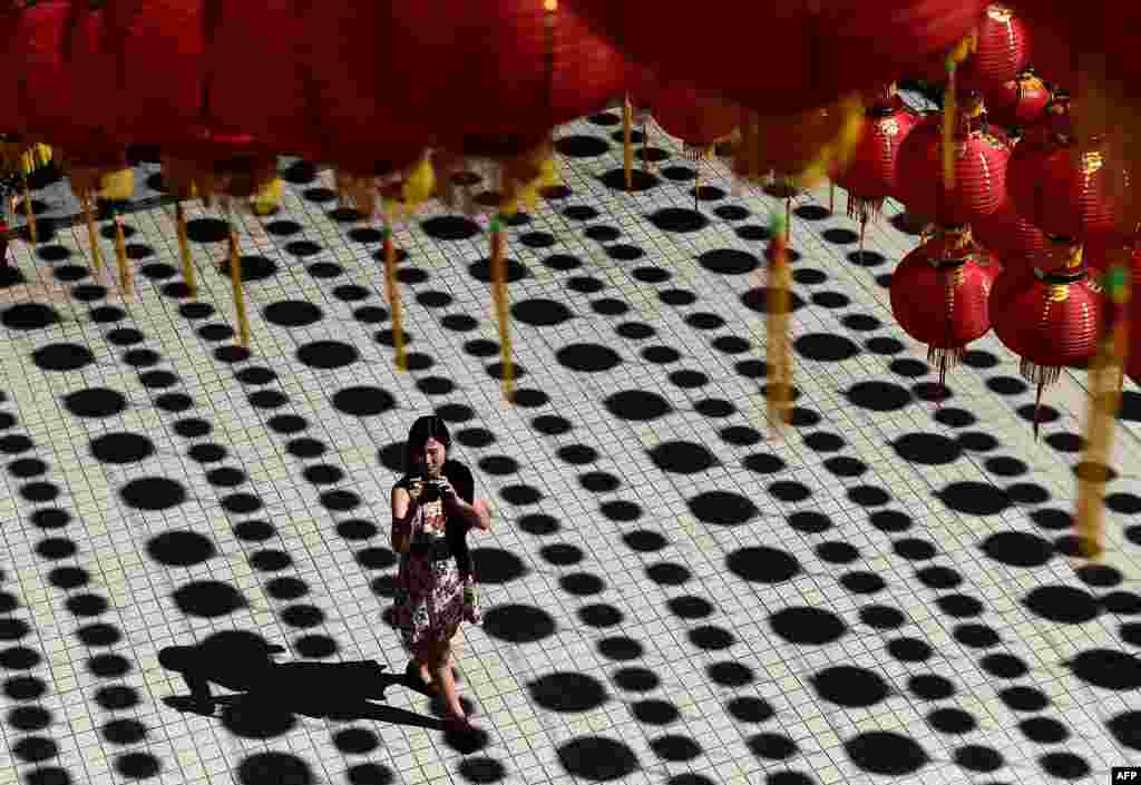 A women takes photographs under traditional Chinese lanterns decorated at the Thean Hou temple ahead of Lunar New Year celebrations in Kuala Lumpur.