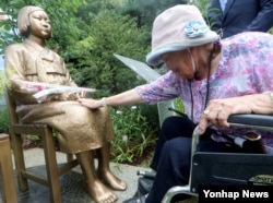 경기도 광명시 광명동굴 평화의 소녀상 앞에서 열린 '평화를 위한 소녀의 꽃밭 조성 협약식'에 참석한 일본군 위안부 피해자 이옥선(91) 할머니가 비에 젖은 소녀상을 어루만지고 있다. (자료사진)