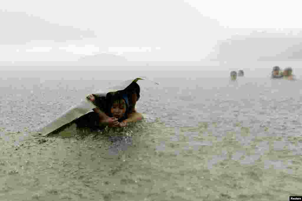 A man and a young girl covers themselves from the rain with a banana leaf in the sea on the outskirts of Colon City, Panama, Oct. 17, 2015.