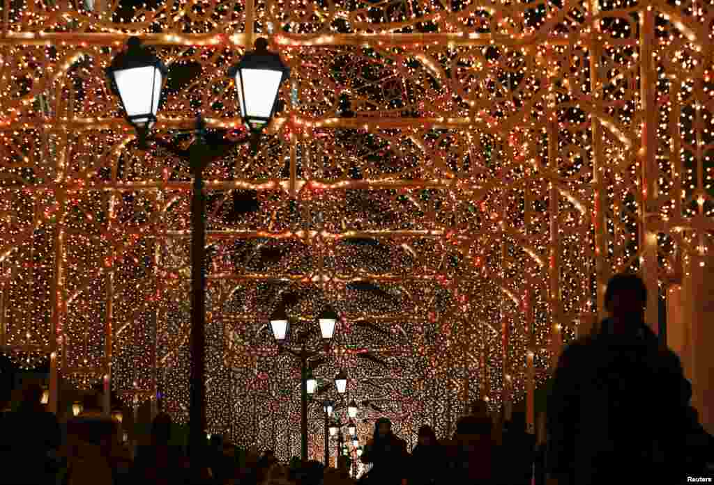 People walk along a street decorated with festive illumination for the New Year and Christmas holidays celebration in central Moscow, Russia.