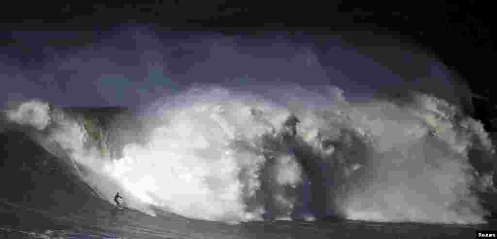 A surfer drops in on a large wave at Praia do Norte in Nazare, Portugal. Praia do Norte has become a famous beach for big wave surfers around the world since Hawaiian surfer Garrett McNamara achieved a world record for the largest wave surfed in 2011.