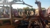 FILE - People walk past a destroyed vehicle following shelling by the Rapid Support Forces in Omdurman, Sudan, on Dec. 10, 2024. An attack on a hospital in Al-Fashir on Dec. 13 killed nine people, World Health Organization officials say. (Khartoum State Government via Reuters) 