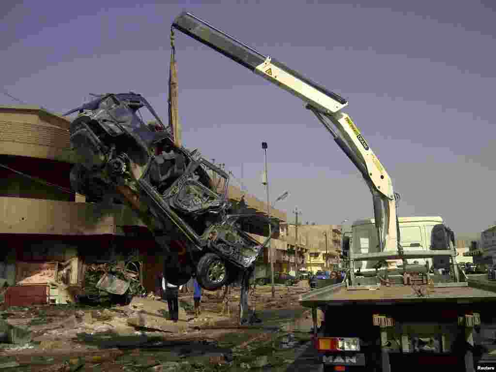A burnt vehicle is removed from the site of a bomb attack that killed Shi'ite pilgrims making their way to a religious festival in Baghdad, Iraq, June 13, 2012.