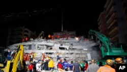 Members of rescue services search in the debris of a collapsed building for survivors in Izmir, Turkey, Oct. 31, 2020. A strong earthquake struck Friday in the Aegean Sea between the Turkish coast and the Greek island of Samos.