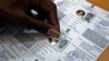 An election staff member pastes a hologram on a voter identification card at an election branch of a district administrative office in the western Indian city of Ahmedabad, April 4, 2014. 