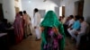 A woman holds a veil over her face and waits for her identity card to be checked before she is allowed to vote in Chandeni, in the northern Indian state of Haryana, April 10, 2014.