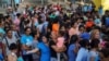 Migrants, many of whom were returned to Mexico under the Trump administration's "Remain in Mexico" policy, wait in line to get a meal in an encampment near the Gateway International Bridge in Matamoros, Mexio, Aug. 30, 2019.
