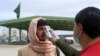 FILE - A health worker takes the temperature of a Afghan national at the Chaman crossing point on the Pakistan-Afghanistan border, in Chaman, Pakistan, Feb. 26, 2020.