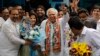 Congress party leader Kapil Sibal, center and his wife Promila Sibal flash victory signs as supporters present them with flower bouquets after Sibal filed his nomination papers for the upcoming parliamentary elections in New Delhi, India, March 20, 2014.