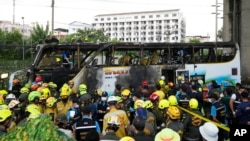 Rescuers inspect a bus that caught fire as it was carrying young students with their teachers, in suburban Bangkok, Oct. 1, 2024. 