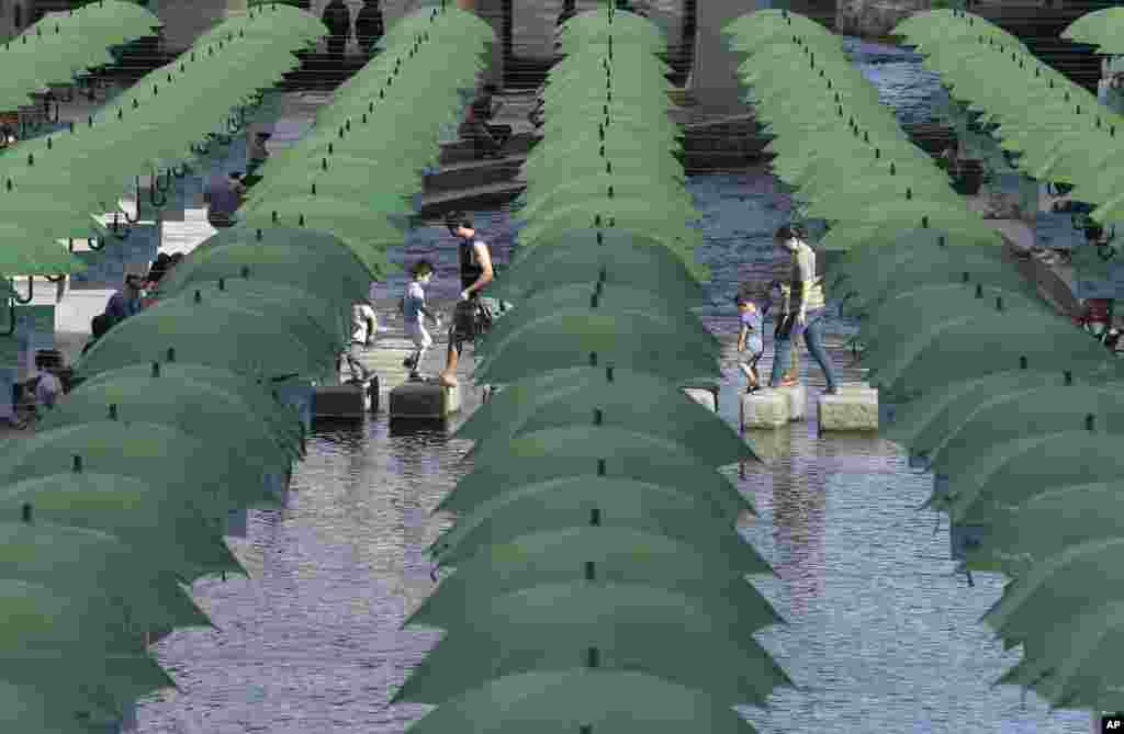 Visitors walk under umbrellas on display over Cheonggye stream during a campaign to raise donations to help underprivileged children in Seoul, South Korea.