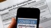 In this illustration photo taken May 08, 2020, a COVID-19 Unemployment Assistance Updates logo is displayed on a smartphone against the backdrop of an application for unemployment benefits, in Arlington, Virginia.