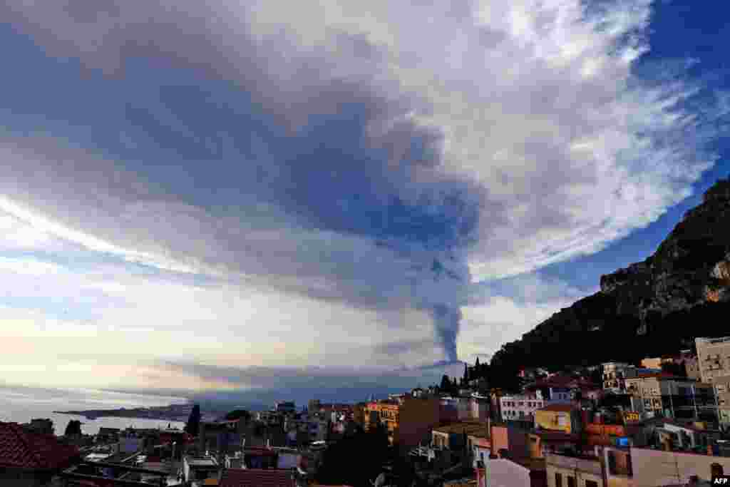 Smoke rises over the city of Taormina, Italy, during an eruption of the Mt. Etna, one of the most active volcanoes in the world, near Catania.