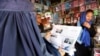A woman reads a local newspaper displaying a photo of U.S. President Donald Trump on its front in Kabul, Afghanistan, Aug. 22, 2017. 