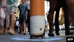 Shoppers walk past a bollard painted to represent a cigarette butt to raise awareness about new no smoking zones in Sydney, Sept. 26, 2016. A new program designed for indigenous Australians is helping lower their high rates of smoking.
