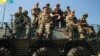Ukraine's Prime Minister Arseniy Yatsenyuk, center, surrounded by U.S. and Ukrainian soldiers atop an armored personnel carrier in Lviv region, western Ukraine, June 3, 2015.