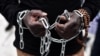 FILE - An African migrant with his hands chained takes part in a march toward the offices of the European Union during a demonstration on Dec. 2, 2017, in central Athens, protesting against the slavery of migrants in Libya.