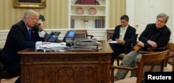 U.S. President Donald Trump, seated at his desk with National Security Advisor Michael Flynn and senior advisor Steve Bannon, right, speaks by phone with Australia's Prime Minister Malcolm Turnbull in the Oval Office at the White House, Jan. 28, 2017.