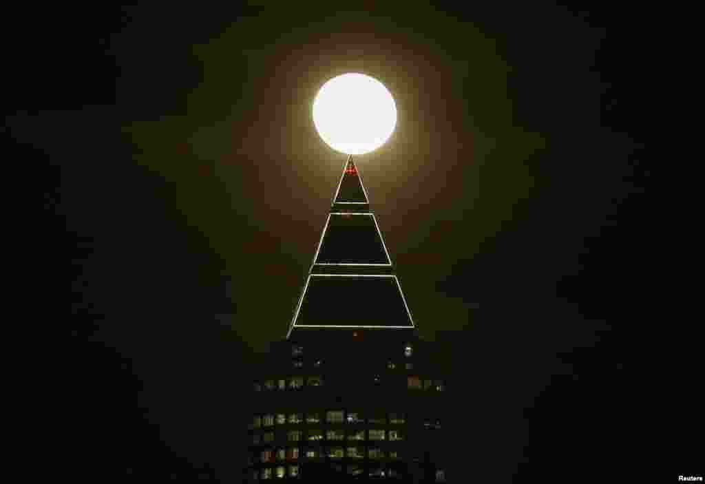 The moon is seen next to the Messeturm (fair tower) in Frankfurt, Germany, Jan. 25, 2016.