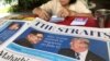 A news vendor counts her money near a stack of newspapers with a photo of U.S. President Donald Trump, right, and North Korea's leader Kim Jong Un on its front page on May 11, 2018, in Singapore. 