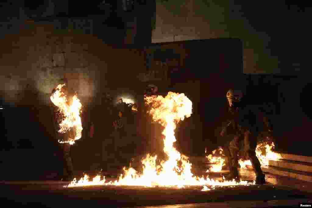Seorang demonstran bertopeng melemparkan bom molotov ke arah polisi anti huru-hara di luar gedung parlemen di Athena, saat anggota parlemen Yunani melakukan voting &#39;program penghematan&#39;.