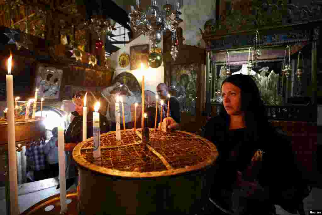A worshiper lights candles inside the Church of Nativity, ahead of Christmas in the West Bank city of Bethlehem.