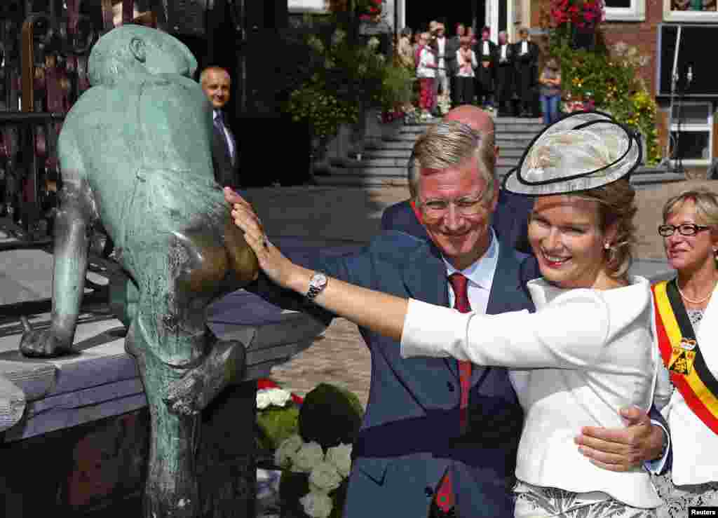 Belgium&#39;s Queen Mathilde (R) and King Philippe (C) touch a statue called &#39;Maca&#39; during their Joyous Entry, a local name used for the royal entry, in the province of Walloon Brabant in Wavre. 
