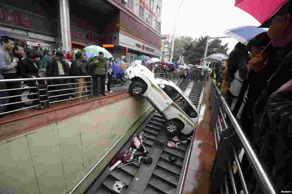 People look on after a car falls onto the stairs of an underpass, in Fuzhou, Fujian province, China, Dec. 9, 2015. The driver backed the car into the underpass entrance after mistaking the accelerator as the brake. No one was injured in the accident, local media reported.