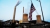 FILE - The U.S. flag flies on a towboat as it passes a coal-fired power-plant on the Ohio River in Moundsville, West Virginia, Sept. 10, 2017. 