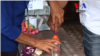 មន្ត្រី​បោះឆ្នោត​​ជួយ​អ្នក​បោះឆ្នោត​​ជ្រលក់​ម្រាមដៃ​​ក្នុង​​ទឹកខ្មៅ​ ​ក្រោយ​ពី​បាន​បោះ​ឆ្នោត​ហើយ។​​